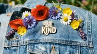 Denim jacket decorated with colorful wildflowers and a Be Kind badge, symbolizing positivity, kindness, and summer bohemian style.