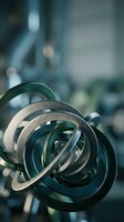 Abstract metallic spiral sculpture with curved ribbons in modern industrial setting with blurred machinery background for contemporary design projects.