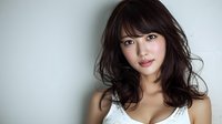 Young Asian woman with long dark hair and bangs against light background, wearing white lace top, looking directly at camera with natural makeup.