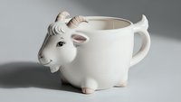 White ceramic goat-shaped mug with horns and tail, novelty animal drinkware for coffee tea hot beverages, cute kitchen accessory gift item.