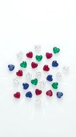 Collection of colorful heart-shaped and round cut gemstones including emeralds, rubies, sapphires and diamonds arranged on white background for jewelry design.