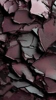 Crushed burgundy eyeshadow powder fragments creating abstract textured pattern with dramatic shadows and metallic sheen, macro photography closeup.