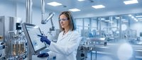Female scientist in white lab coat working with microscope in modern research laboratory conducting scientific analysis and medical testing.