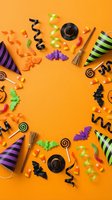 Halloween party decorations and candy arranged in circular frame on bright orange background with copy space for festive celebration design.