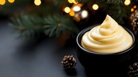 Creamy soft serve vanilla ice cream swirl in black bowl with pine branches and festive bokeh lights creating cozy winter holiday atmosphere.