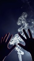 Silhouette of hands reaching toward ethereal white smoke swirls against dark blue background creating mystical atmospheric effect for creative projects.