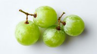 Fresh green grapes cluster with water droplets on white background, isolated organic fruit for healthy eating and nutrition concepts.
