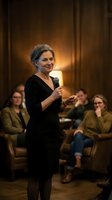 Confident mature businesswoman speaking with microphone at corporate conference presentation to engaged audience in elegant meeting room.