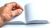 Open blank book with male hand turning white page against light background, showing empty pages ready for content and design mockups.