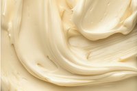 Creamy vanilla frosting background with smooth swirls and soft waves creating luxurious texture, close-up macro shot showing rich buttery consistency.