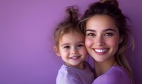 Happy young Caucasian mother and toddler daughter embracing against purple background. Loving family portrait showing maternal bond and childhood joy.