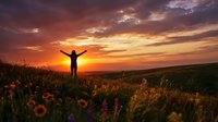 Person with raised arms celebrating freedom at golden sunset in wildflower meadow. Silhouette against dramatic sky with warm colors and peaceful landscape.