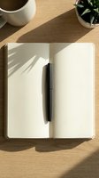 Open notebook with blank pages and black pen on wooden desk with coffee cup and potted plant, natural sunlight casting shadows, workspace organization and planning concept.