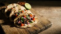 Pulled pork tacos with fresh salsa, cilantro and lime on wooden board, Mexican street food for restaurant menus and culinary content.