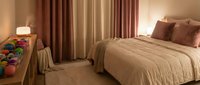 Cozy modern bedroom interior with warm beige tones, comfortable bed, elegant curtains and soft lighting creating peaceful atmosphere for rest and relaxation.