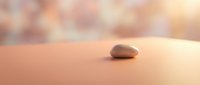 Single smooth stone resting on warm sand with soft, blurred background. Minimalist composition suitable for wellness, meditation, spa, and relaxation design projects.
