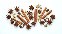 Aromatic baking spices collection with cinnamon sticks, star anise, cardamom pods arranged on white background for culinary and cooking projects.