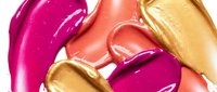 Colorful lipstick smears in pink coral and gold tones creating abstract makeup texture for beauty and cosmetics advertising campaigns.
