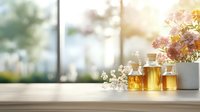 Essential oils and honey in glass bottles on wooden windowsill with fresh flowers and soft natural morning light, creating serene wellness atmosphere.
