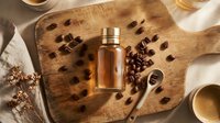 Amber glass bottle with coffee beans on rustic wooden cutting board, warm lighting creates cozy cafe atmosphere for skincare and beauty products.