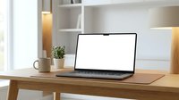 Modern laptop with blank white screen on wooden desk in bright home office workspace with coffee cup and plant for remote work productivity.