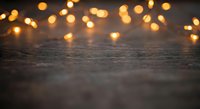 Warm bokeh lights glowing softly above rustic wooden surface creating cozy atmospheric background for holiday decorations and festive celebrations.