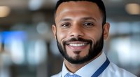 Young African American male professional wearing white dress shirt and blue tie, smiling confidently at camera in modern office environment with blurred background for corporate and business use.