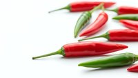 Fresh red and green chili peppers scattered on white background. Hot spicy vegetables for cooking, seasoning and culinary preparations. Isolated produce.