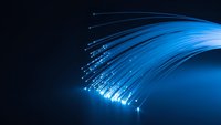 Blue fiber optic cables with glowing light streaks creating dynamic curved lines on dark background for technology and communication concepts.