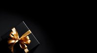 Black gift box with golden ribbon bow on dark background, suitable for holiday, celebration, and luxury product marketing materials.