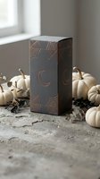 Black gift box with copper spider web and moon designs surrounded by white pumpkins on rustic surface for Halloween seasonal packaging and autumn decor.