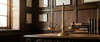 Brass scales of justice and wooden gavel on mahogany desk with law books, symbolizing legal profession, courtroom authority, and judicial system for law firm branding.