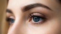 Close-up of woman's blue eyes with natural makeup and well-groomed eyebrows showcasing skincare and beauty routine for cosmetic advertising.