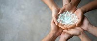 Multiple hands of diverse ethnicities holding glowing lotus flower symbol together, representing unity, healing, meditation, and spiritual wellness for mindfulness and community support concepts.