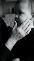 Tender moment between grandmother and baby grandchild in emotional black and white portrait showing intergenerational love and family bonding at home.