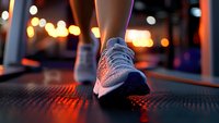 Close-up of athletic running shoe on treadmill with warm bokeh lights in background, capturing evening workout atmosphere at modern fitness gym facility.