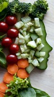 Fresh vegetables arranged on white wooden background including broccoli, cherry tomatoes, cucumber, carrots and lettuce. Close-up view of healthy ingredients for salad.