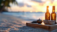 Romantic beach sunset with wine bottles and traditional tea ceremony set on wooden tray in golden sand, waves and palm trees silhouette in background.