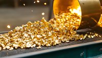 Golden nuggets spilling from metal container onto dark surface, glowing with warm bokeh lights in background, creating luxurious precious metal concept scene.
