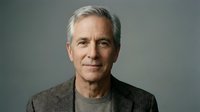 Mature Caucasian man with gray hair wearing casual gray shirt against neutral background, suitable for corporate portraits and professional headshots.