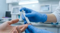 Medical professional in blue gloves administering insulin injection pen to patient hand in clinical laboratory setting for diabetes treatment.