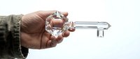 Male hand holding large transparent crystal glass key against white background symbolizing success, solution, opportunity and unlocking potential.