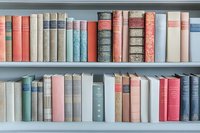 Vintage hardcover books arranged on white shelves, featuring pastel colors of pink, blue, and cream with decorative spines for home library decor.