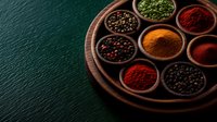 Aromatic spices and seasonings in wooden bowls on round serving board against dark green background. Traditional cooking ingredients for authentic cuisine.