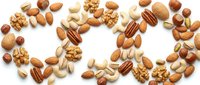 Mixed nuts and seeds collection including almonds, walnuts, pecans, cashews and hazelnuts scattered on white background for healthy snacking and cooking.