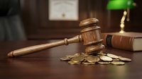Wooden judge gavel with golden coins on dark desk in courtroom setting. Legal justice concept for financial law, bankruptcy, divorce settlements.