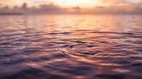 Tranquil ocean waves at golden hour with warm sunset colors reflecting on water surface creating peaceful seascape for meditation and relaxation backgrounds.