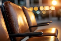 Vintage brown leather cinema seats in empty movie theater with soft bokeh lights in background creating nostalgic atmospheric mood.
