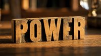 Vintage wooden letterpress blocks spelling POWER on rustic table with warm lighting creating motivational business concept for leadership and strength themes.