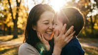 Loving mother and young son sharing tender moment outdoors during golden hour sunset, expressing joy and affection in warm autumn park setting.